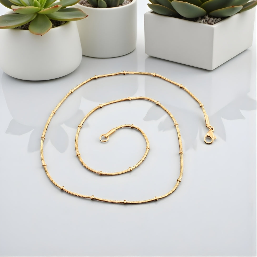 Chaîne homme Serpent avec Perles Subtiles dore presentation table marbre blanc plantes