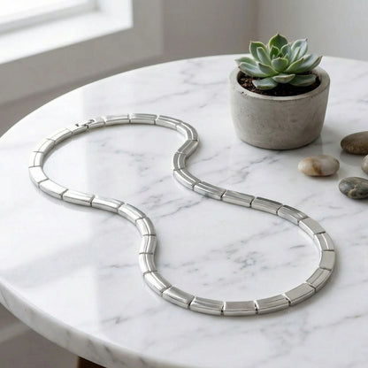 Chaîne, collier homme maille barrette articulee argent table marbre 