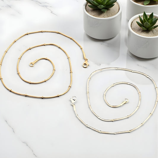 Chaîne homme Serpent avec Perles Subtiles dore argent presentation table marbre blanc plantes