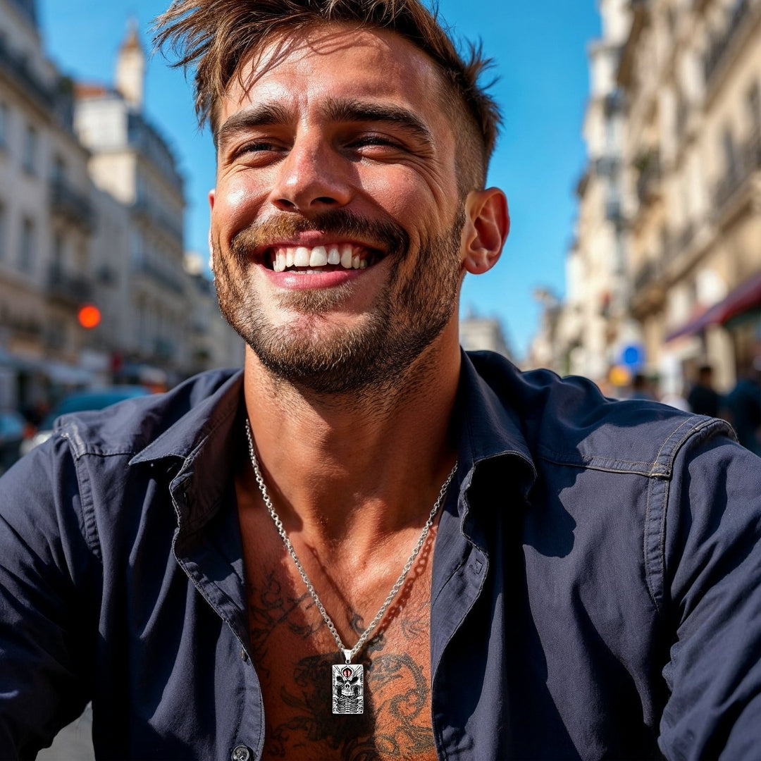 Collier homme- pendentif- tête de mort- skull- homme-élégant-chemise-bleue-barbe-courte- assied- à- Paris