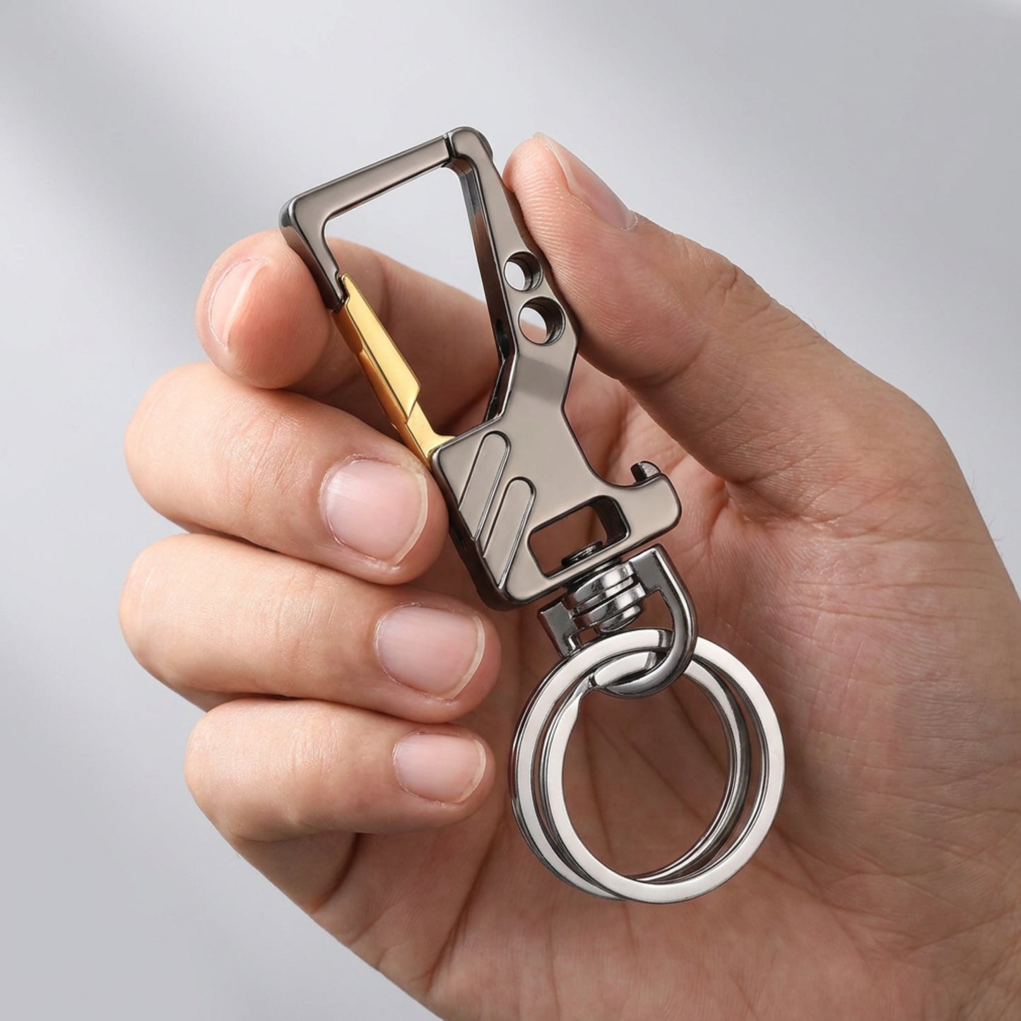 "Main tenant le porte-clé CARABINER finition noir et doré avec anneau rotatif mmihommesmodernes.com"