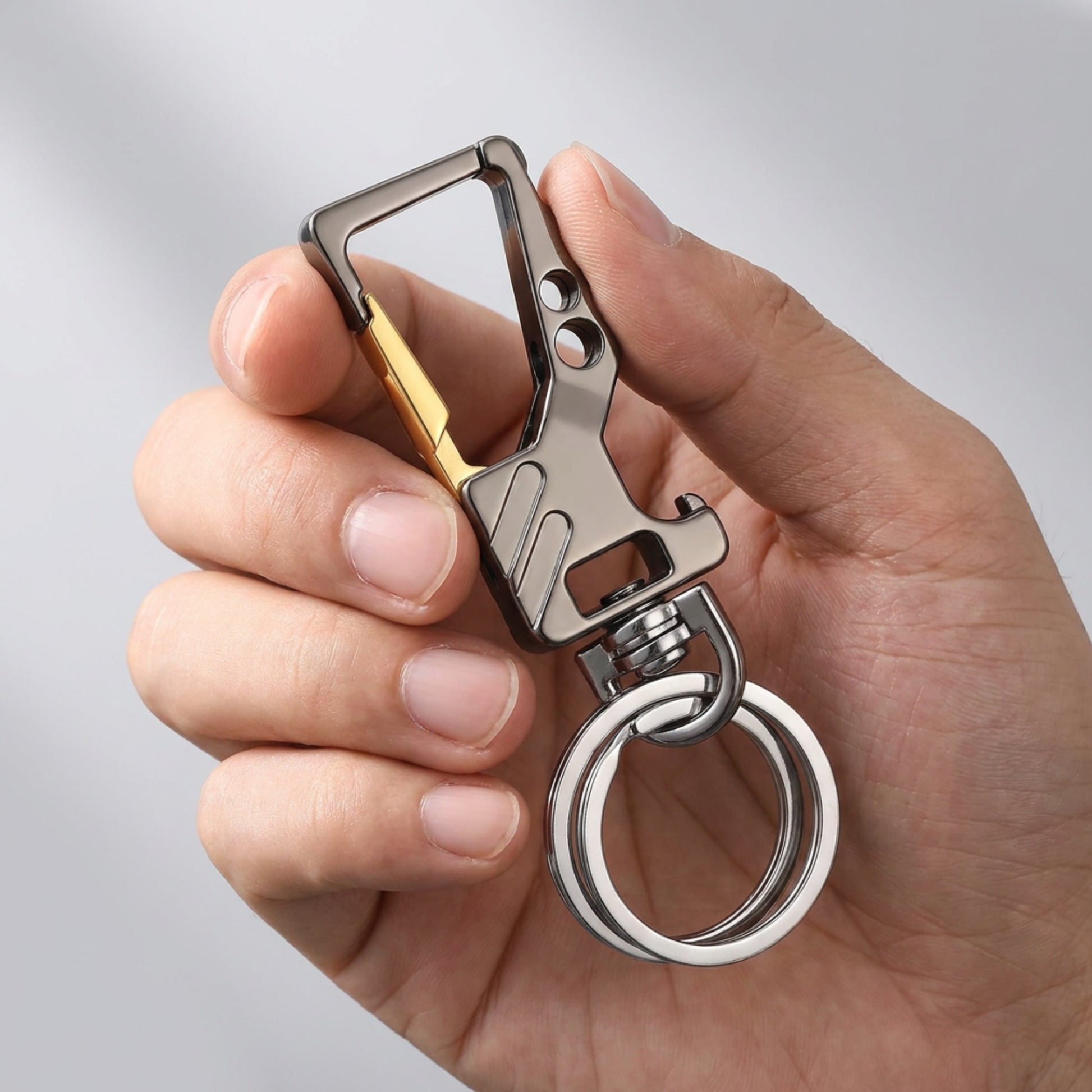"Main tenant le porte-clé CARABINER finition noir et doré avec anneau rotatif mmihommesmodernes.com"