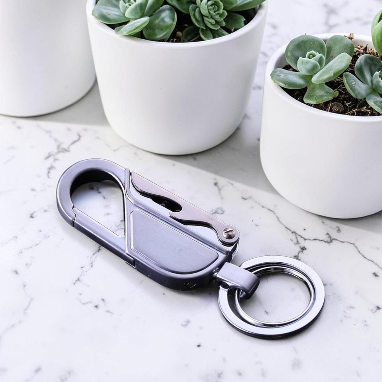 Porte-clé métal mousqueton EDC finition argent posé sur marbre