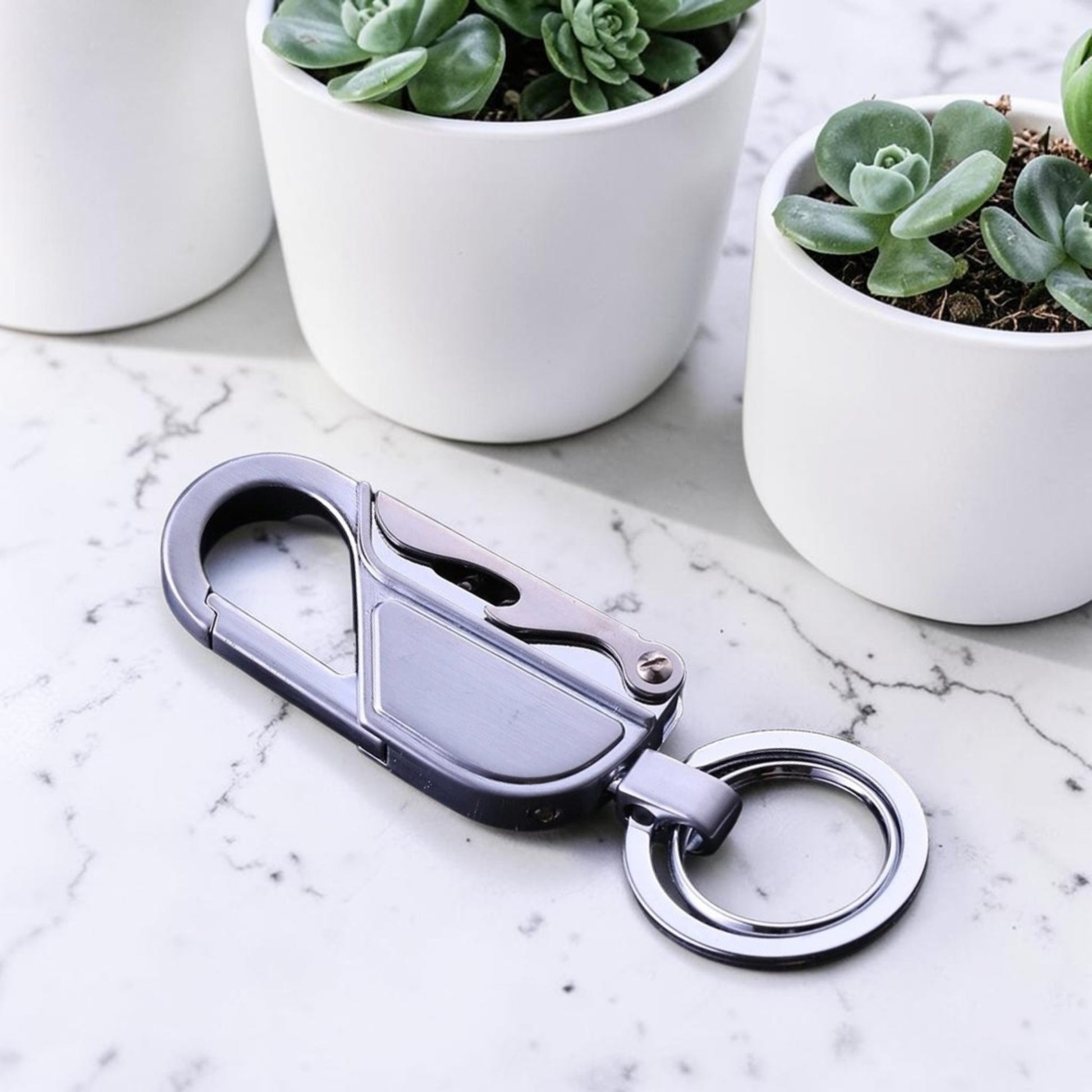 Porte-clé métal mousqueton EDC finition argent posé sur marbre