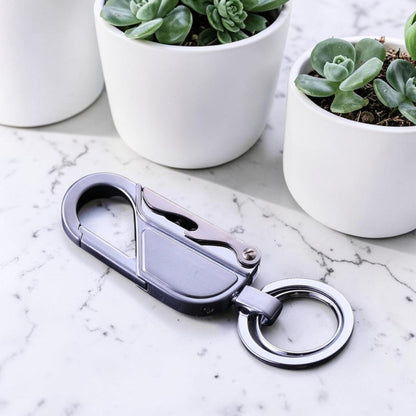 Porte-clé métal mousqueton EDC finition argent posé sur marbre