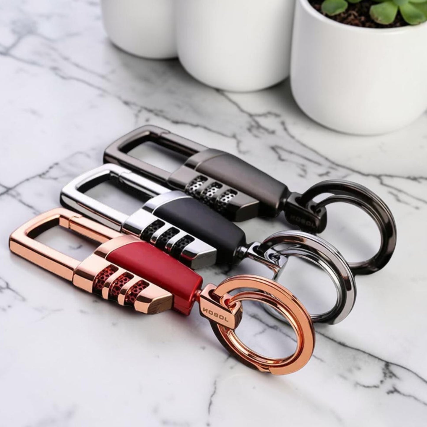 Porte-clés Titan Lock trois variantes dore argent noir sur marbre